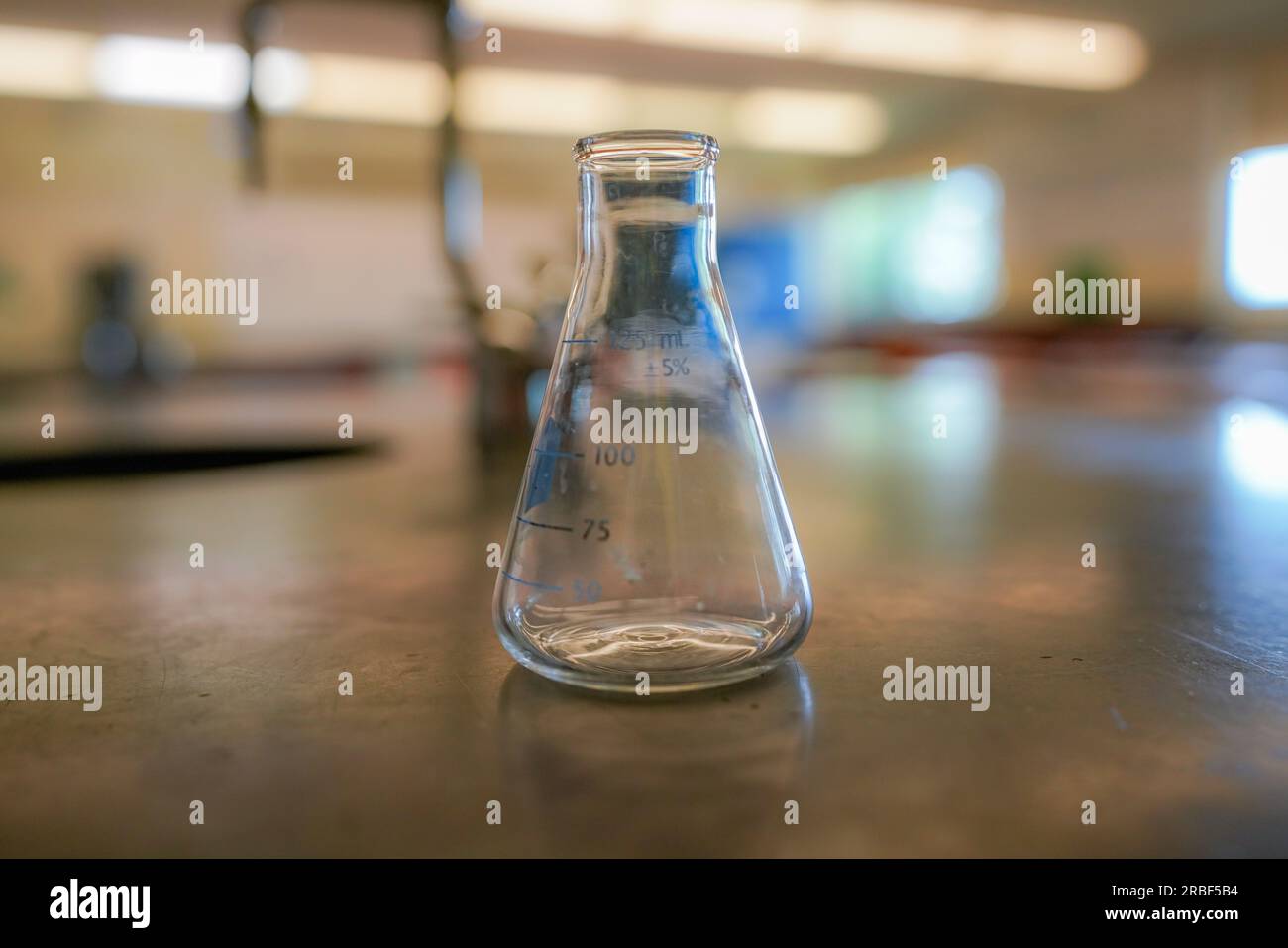 flask on a black resin table with a high school science room background. Stock Photo