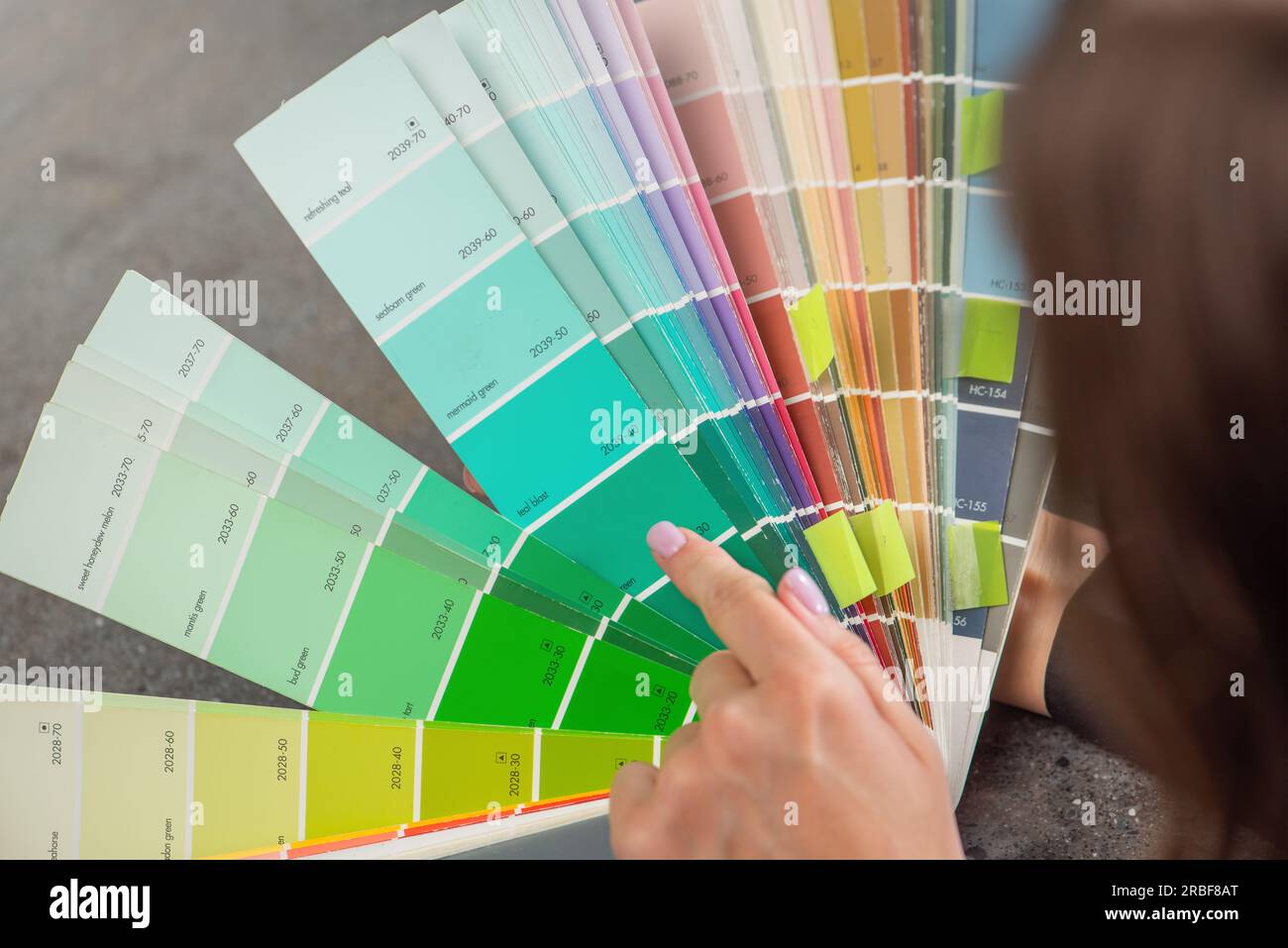 Color selection according to RAL. A woman designer chooses a shade from the RAL color palette. The concept of design work and color selection in the Stock Photo