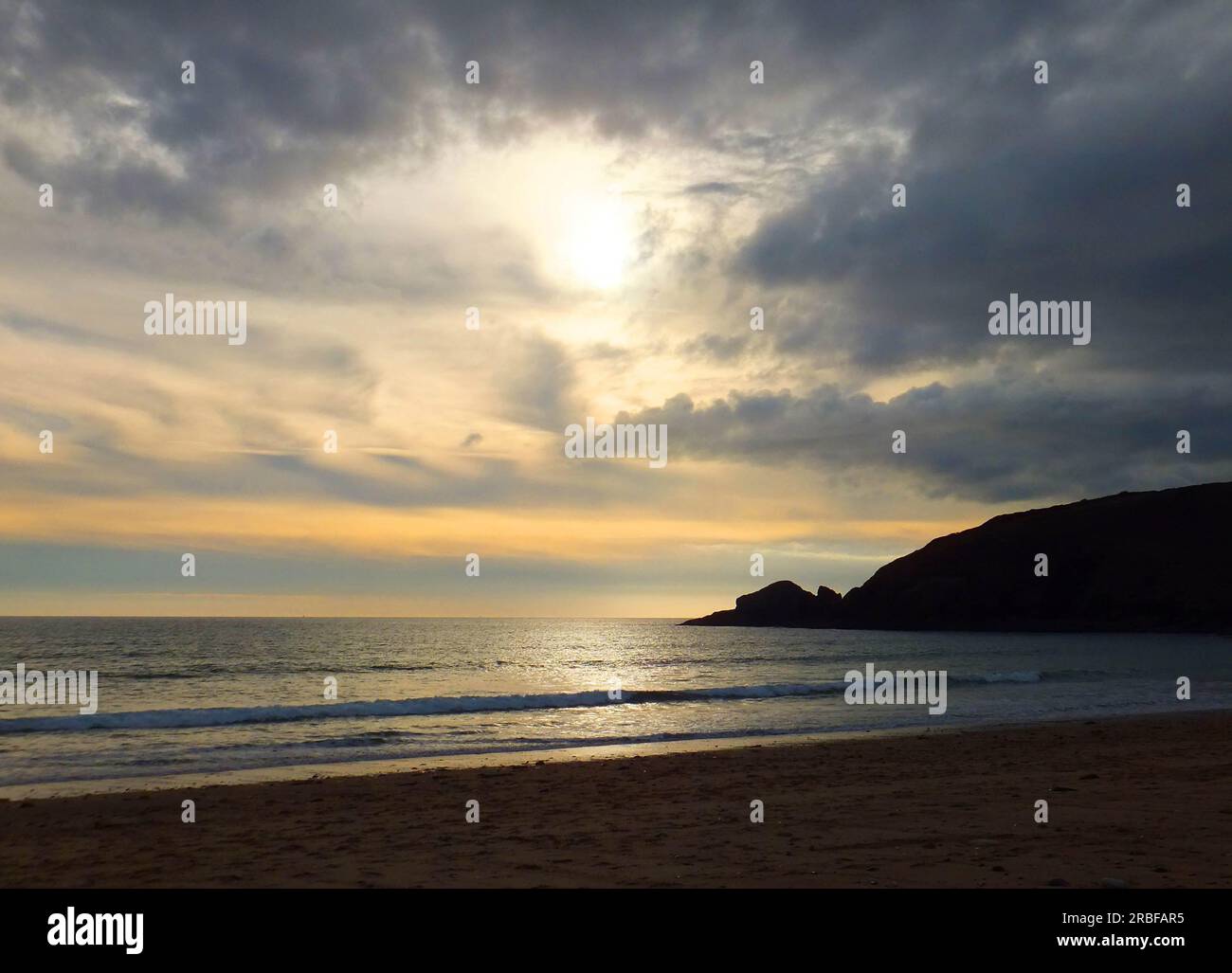 Hoe Point silhouetted against an interesting late afternoon sky in autumn at Praa sands in Cornwall. Stock Photo