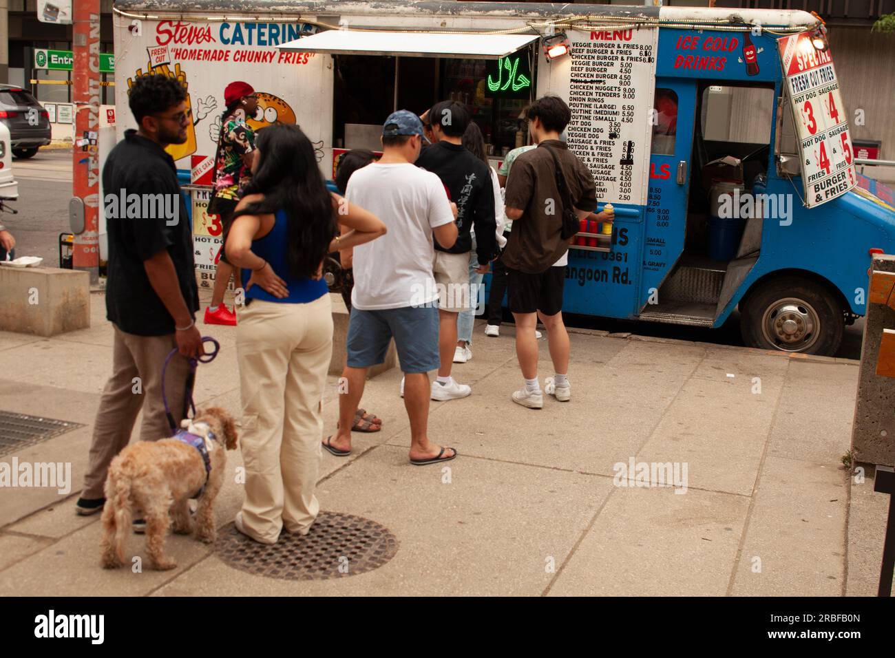 Toronto Canada - July 8, 2023:   People  are lining up to buy  some food from a Food track at Queen Street near to Nathan Phillips Square  and City Ha Stock Photo