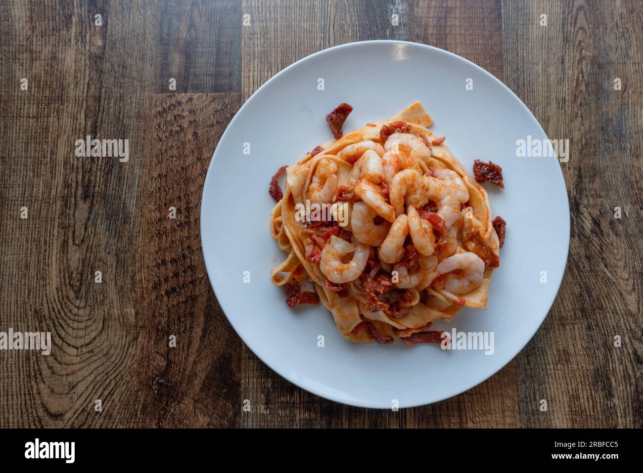 Tagliatelle pasta with sundry tomato and shrimp.Top view on a wooden table. Stock Photo
