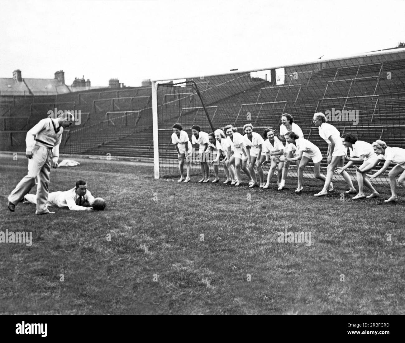 Newcastle, England:  1937 A women's soccer team lines up in front of the goal to block a kick. Stock Photo