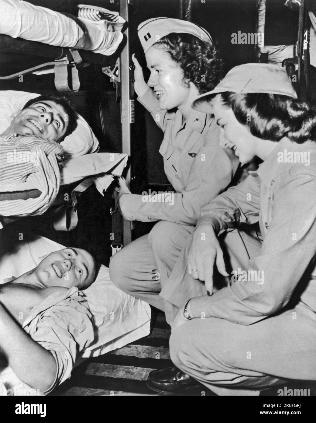 Korea:  April 20, 1951 Two wounded soldiers are comforted by nurses of the air evacuation team. Sixty three patients were transported to California on fifty hour flight on a C-97 transport plane. Stock Photo