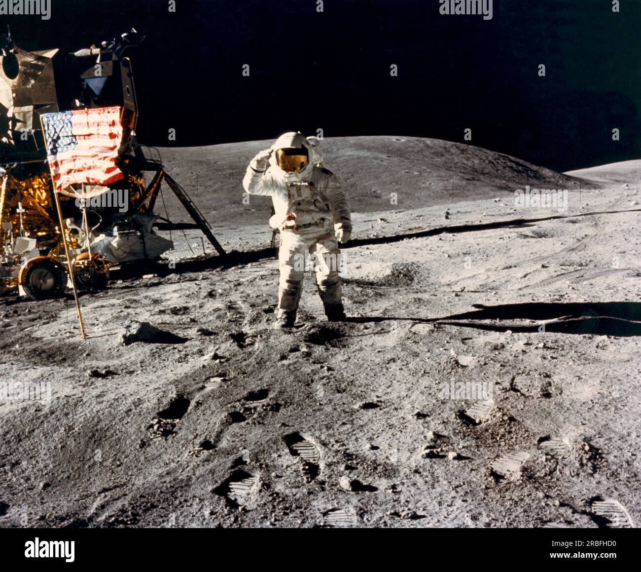 Moon:  April 21, 1972 Astronaut Charles Duke Jr.,  Apollo 16 lunar module pilot, salutes the U.S. flag at the Descartes landing site during the mission's first extravehicular activity. The Lunar Module and the Lunar Roving Vehicle are at the left. Stock Photo