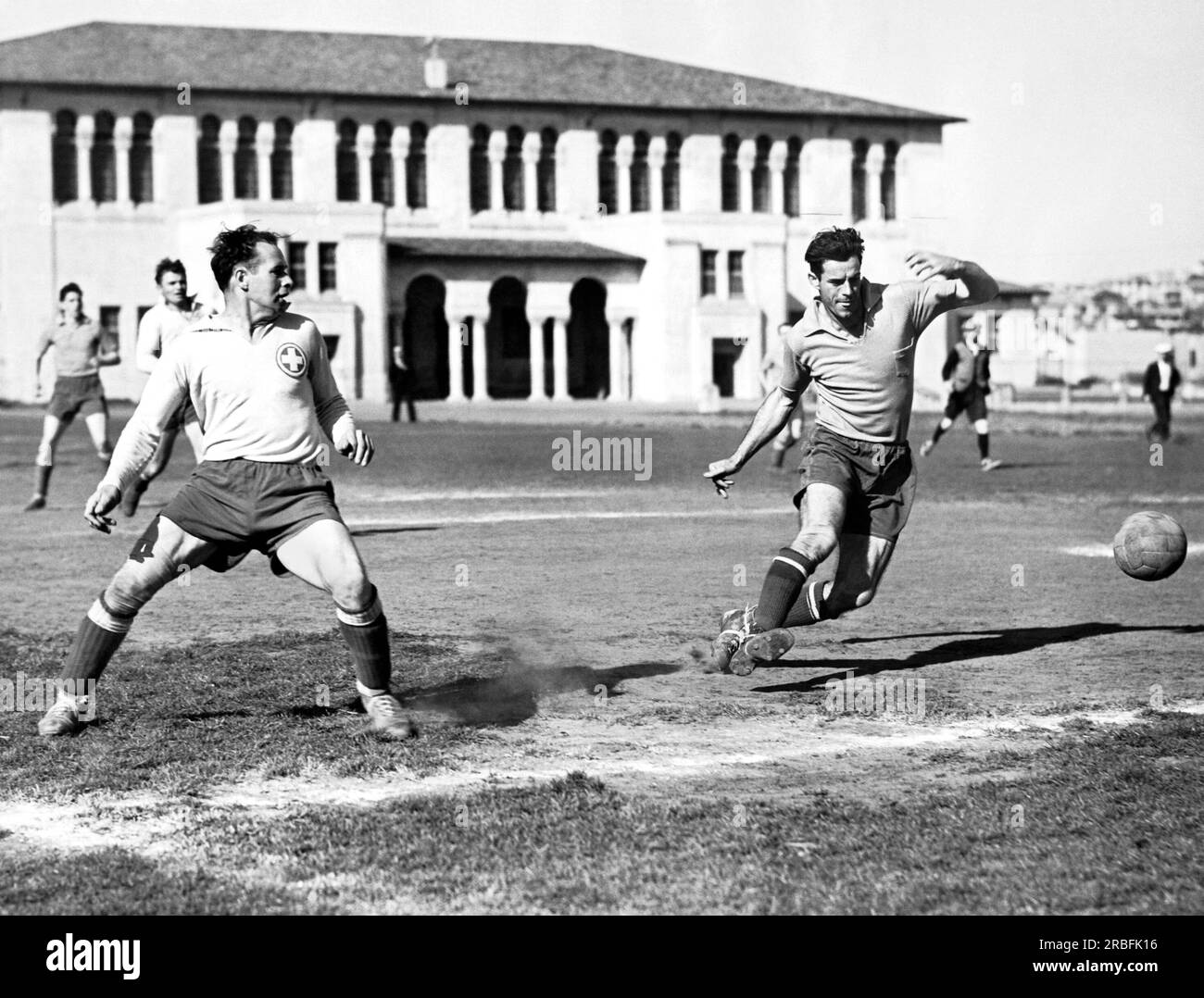 San Francisco, California:  April, 1939 Swiss A.C. Rover soccer star Alastain Finlayson kicks in a C.F.A. semifinal game in front of the Beach Chalet at Golden Gate Park. Stock Photo