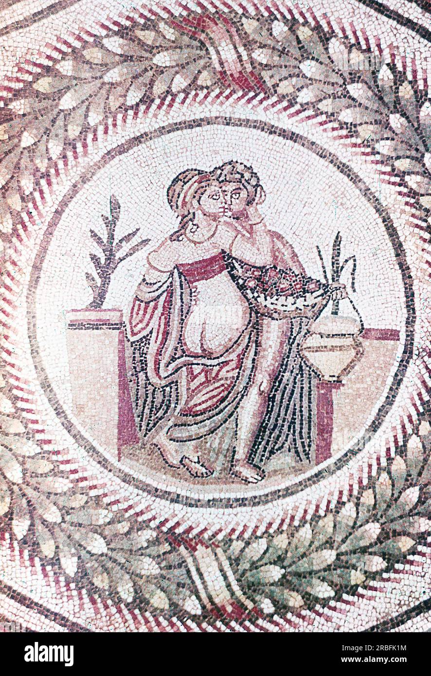 This photo of a mosaic showing a detail from a bedroom scene was taken in the summer of 1970 at Piazza Armerina in Sicily. Piazza Armerina is home to the Roman Villa del Casale and its famous mosaics, the 'finest mosaics in situ anywhere in the Roman world,' as described by UNESCO, which inserted it into its World Heritage list in 1997. Villa Romana was a lavish patrician residence built at the center of a huge latifundium (agricultural estate) at the end of the 4th century AD. It is thought to have belonged to a member of the Roman senatorial aristocracy, who traded in exotic animals.  The vi Stock Photo