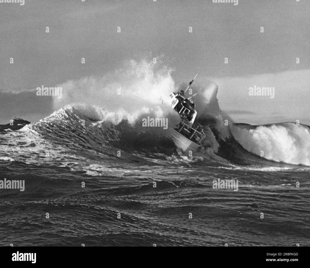 United States:  c. 1954 A Coast Guard surf rescue boat plunges into a breaking wave. Stock Photo