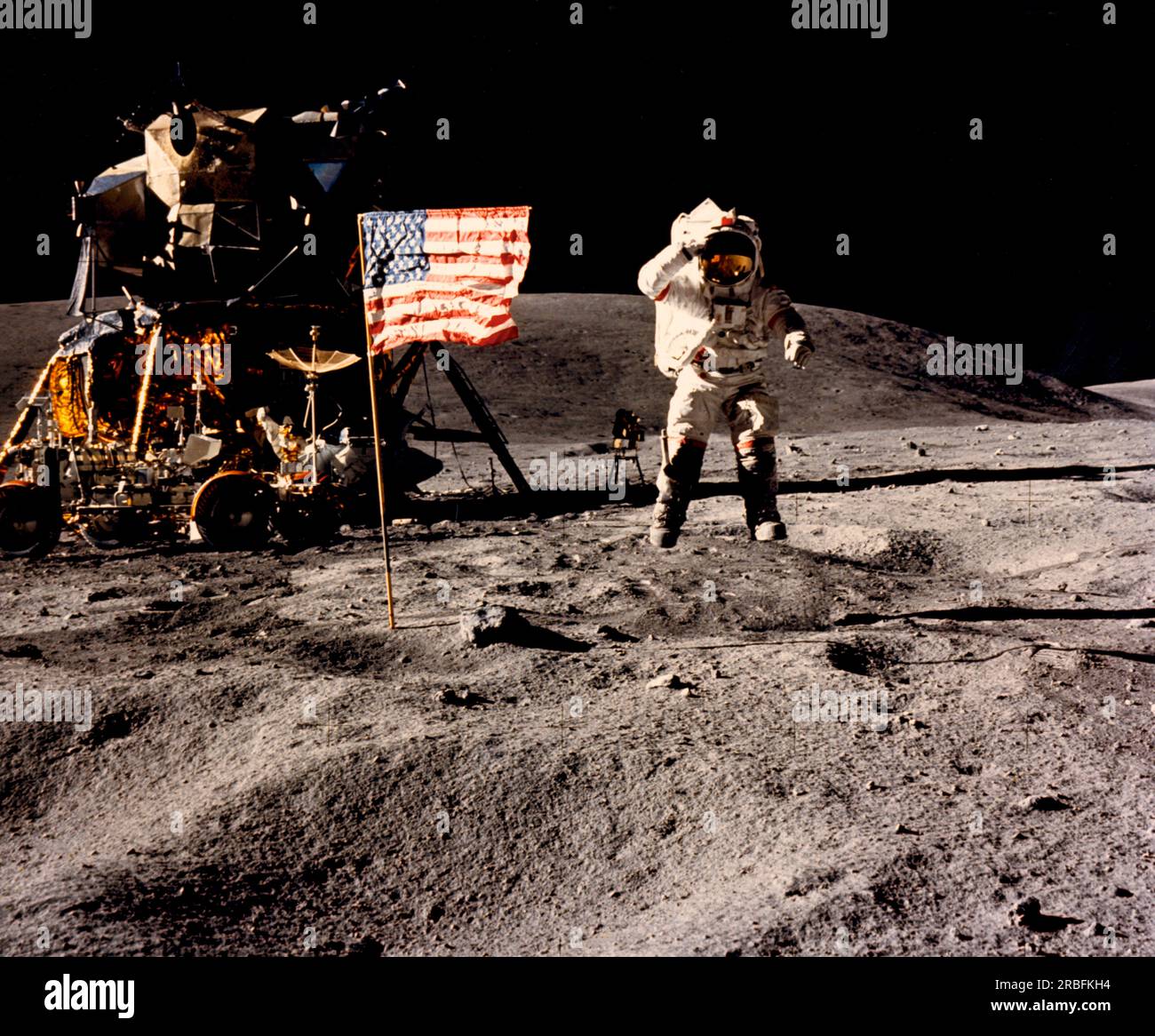 Moon:  April 21, 1972 Astronaut John Young,  commander of the Apollo 16 lunar landing mission, leaps from the lunar surface as he salutes the U.S. flag at the Descartes landing site during the mission's first extravehicular activity. The Lunar Module and the Lunar Roving Vehicle are at the left. Stock Photo