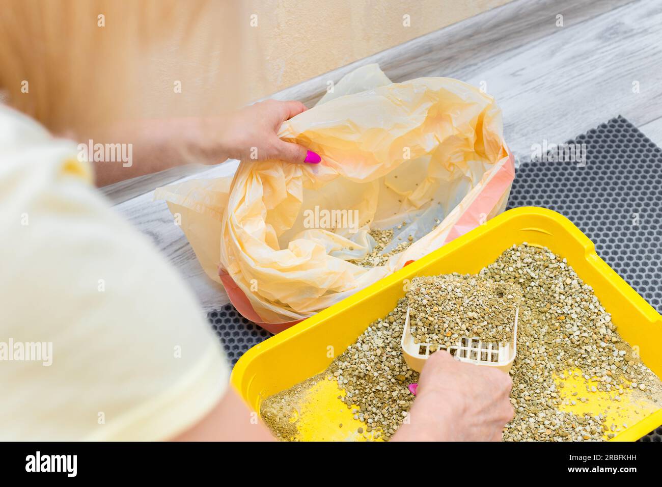 woman pouring used cat litter into trash bag. woman changing cat litter