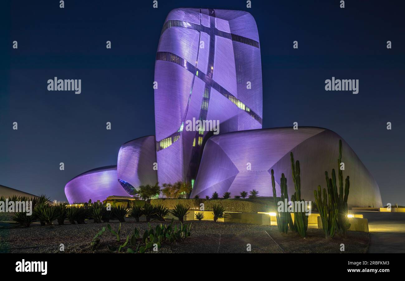 Illuminated during the night modern building in the center of Al Khobar with green cactuses in the foreground, Saudi Arabia Stock Photo