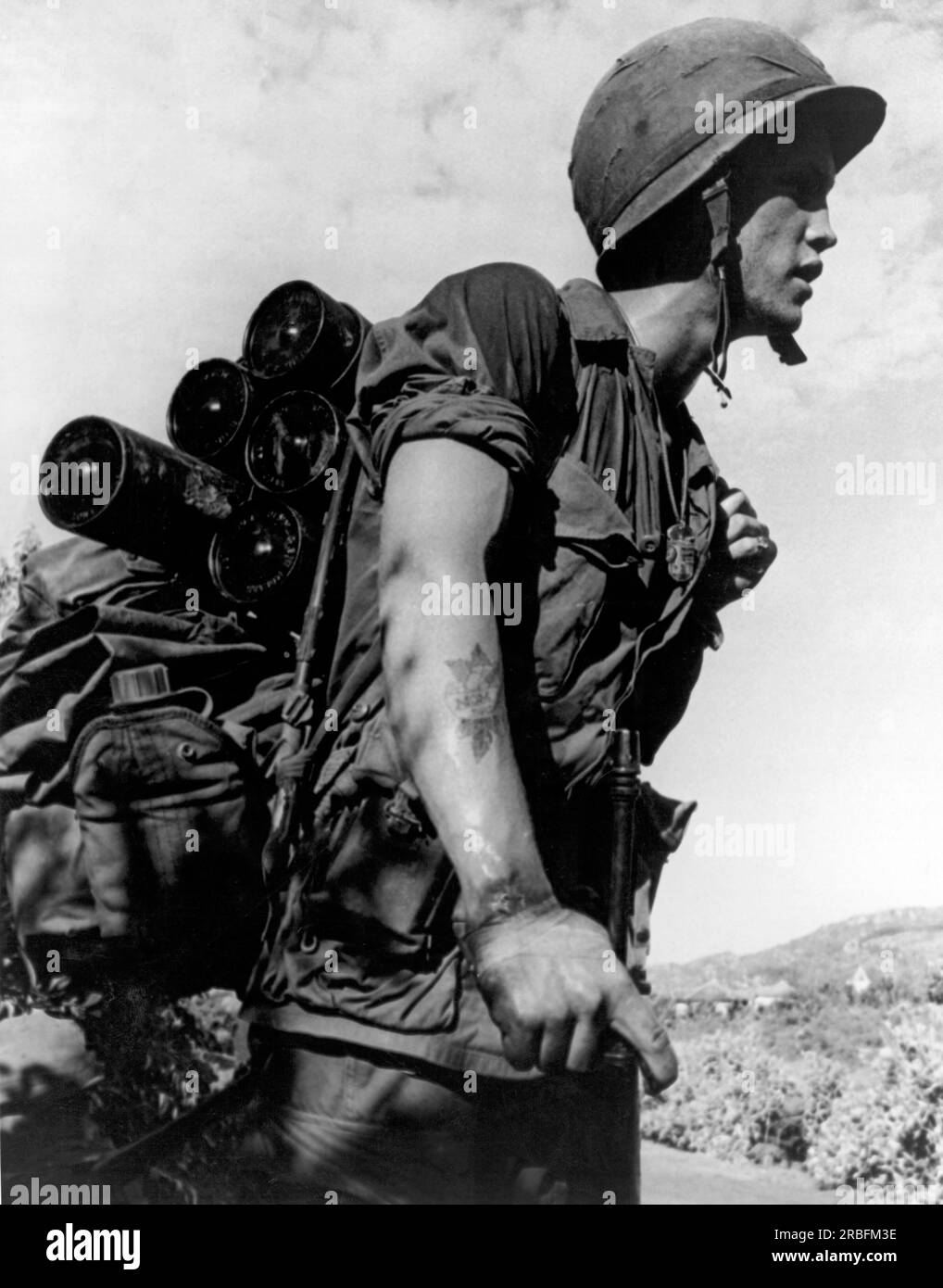 Vietnam:   August, 1966 A soldier of the 173rd Airborne Brigade carrying a load of five mortar rounds, four canteens, poncho and an entrenching tool on a search and destroy mission. Stock Photo