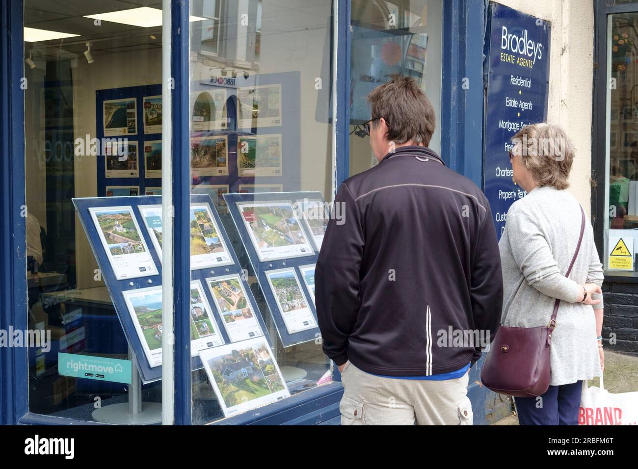 Penzance is a small twon in the south west of Cornwall UK. Two people looking into an esate agents window Stock Photo