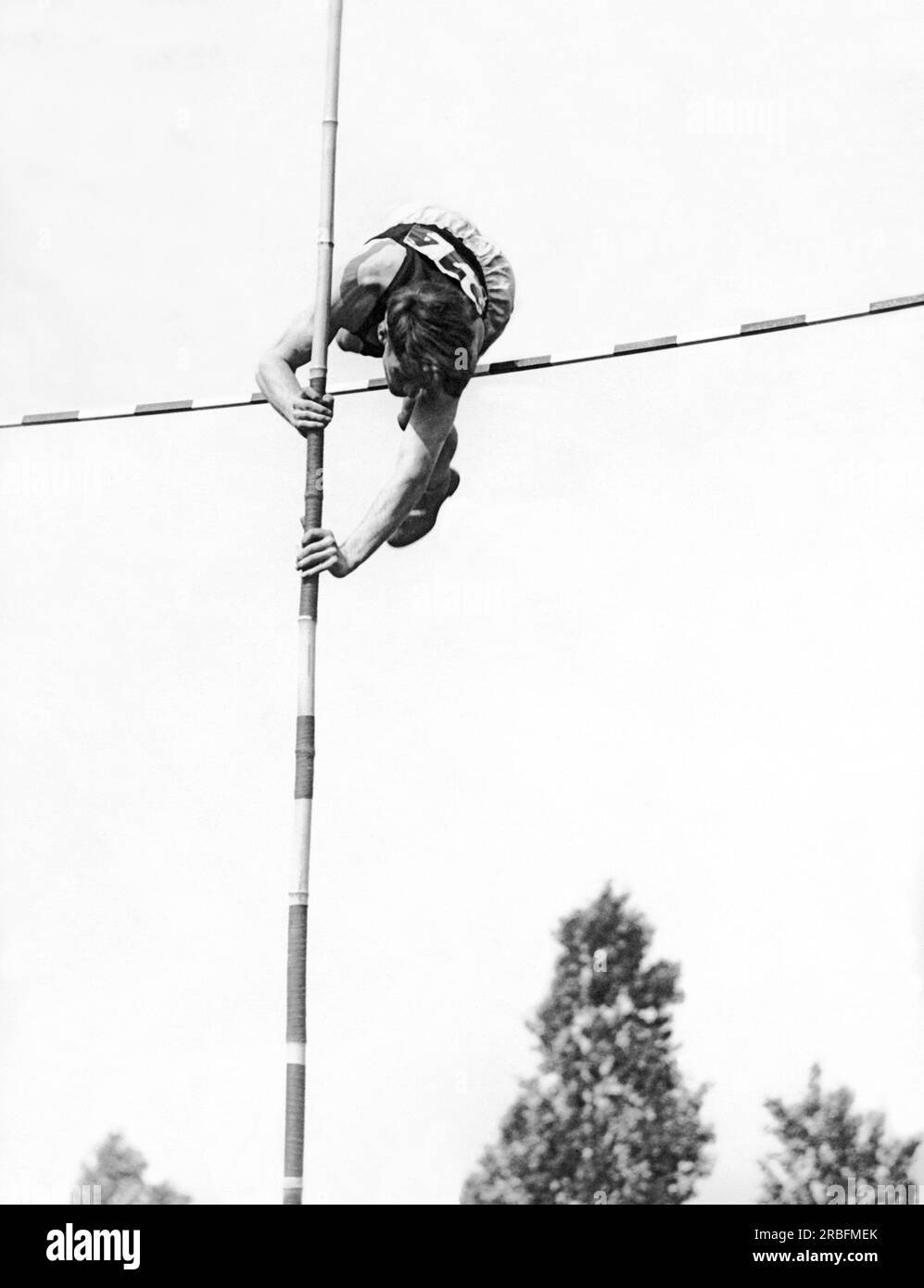 United States: c. 1934 A pole vaulter as his body clears the bar Stock