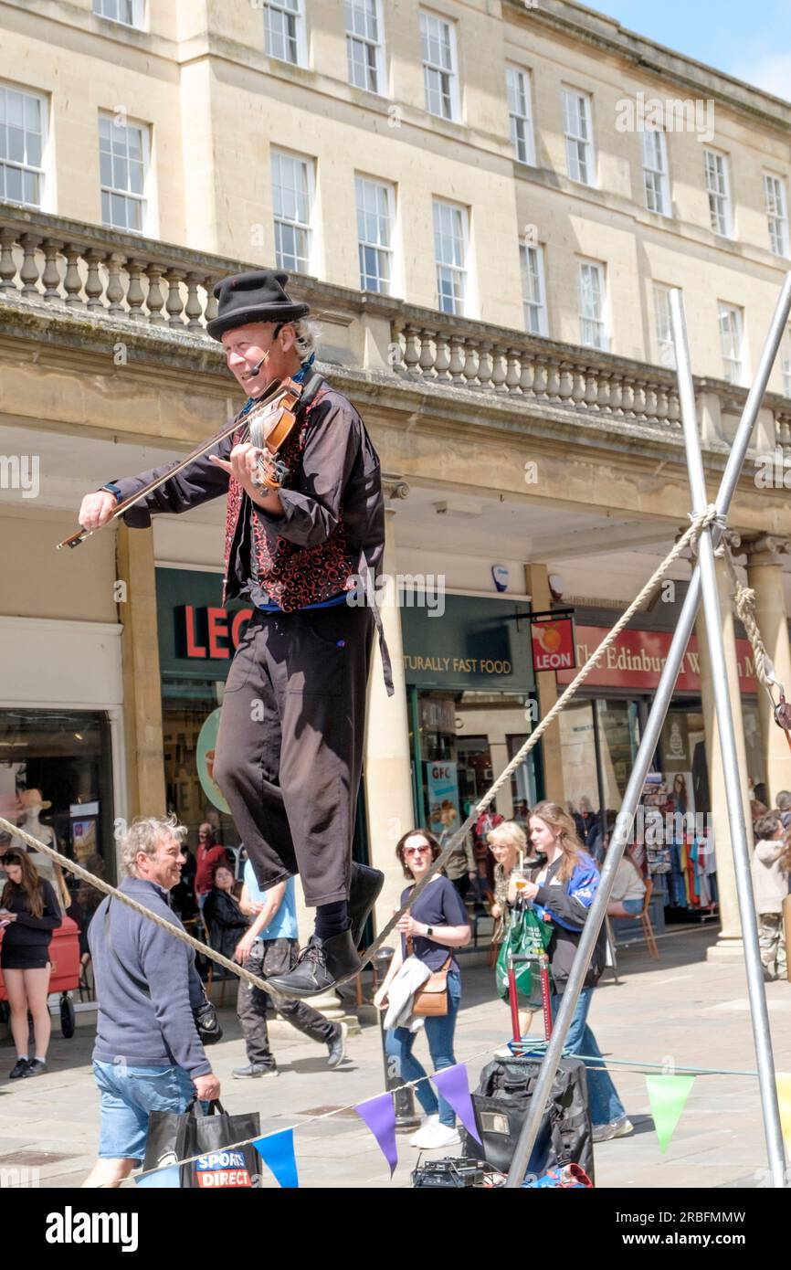 Kwabana Lindsay performs his act in the center of Bath. Playing a violin whist walking a slack rope. Stock Photo