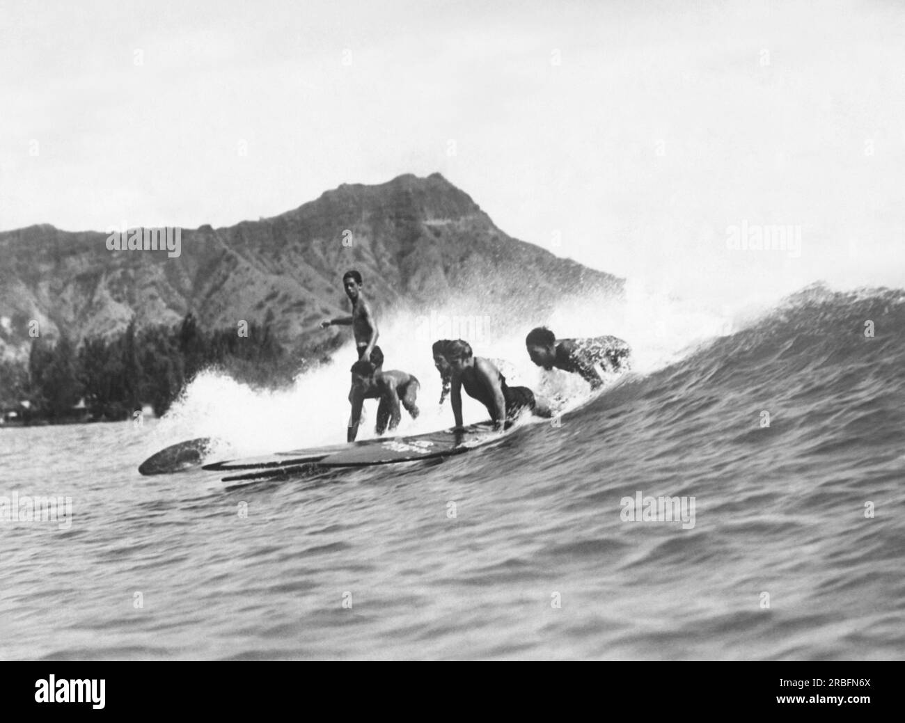 Honoluly, Hawaii:  c. 1925 Native Hawaiians riding their surfboards at Waikiki Beach with Diamond Head in the background. Stock Photo