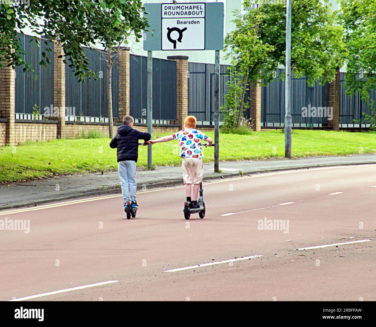 young kids in the middle of the road on electric scooters Stock Photo