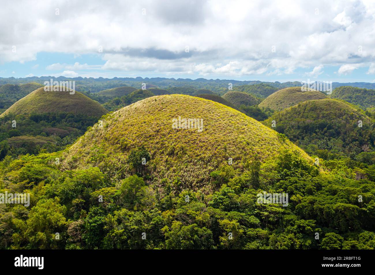 Unique place. Chocolate Hills, Bohol, Philippines. Blue sky with clouds, dome shaped limestone cliffs Stock Photo