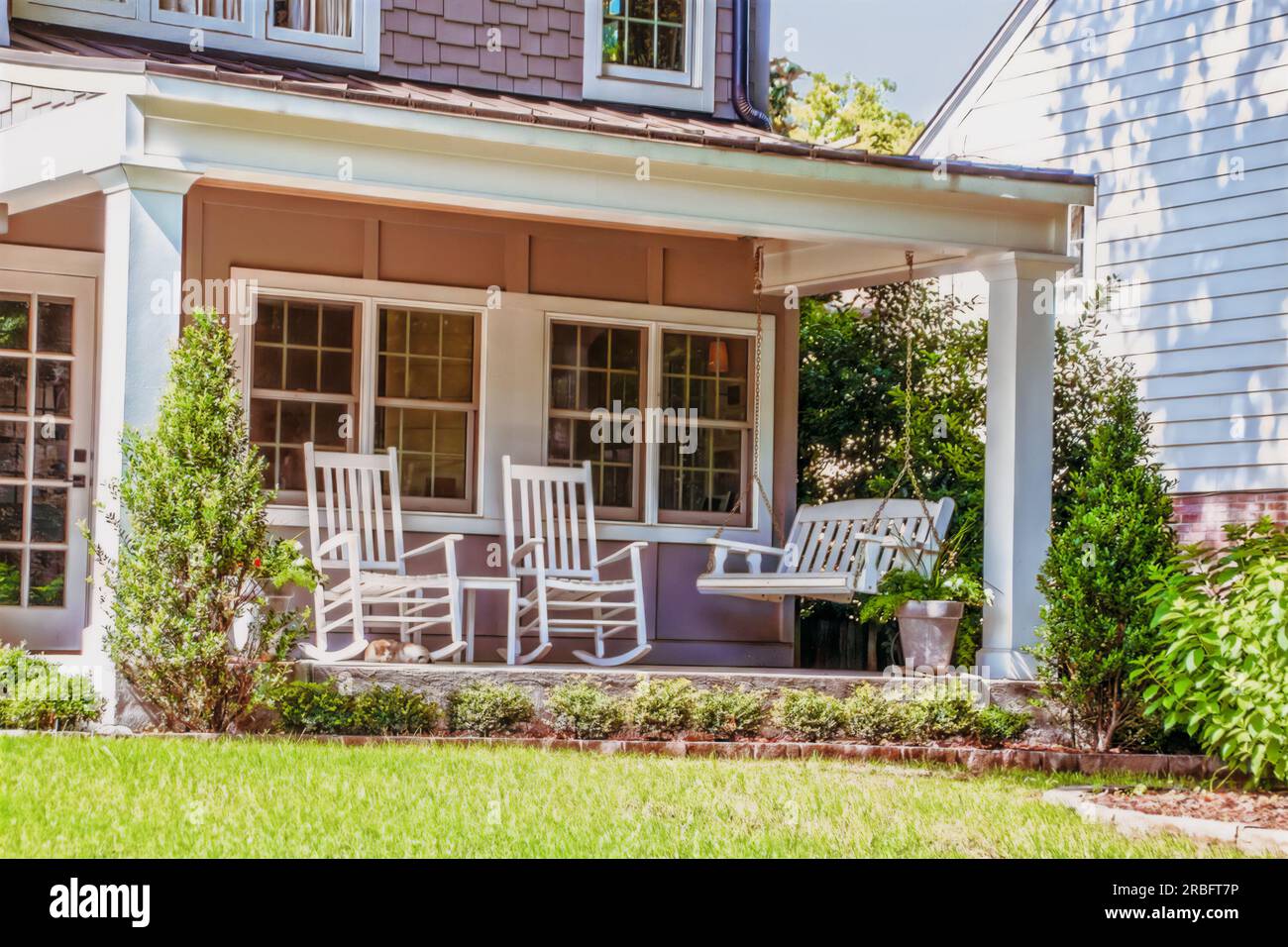 Front Porch America Porch Swing and two rocking chairs and a cat Stock Photo