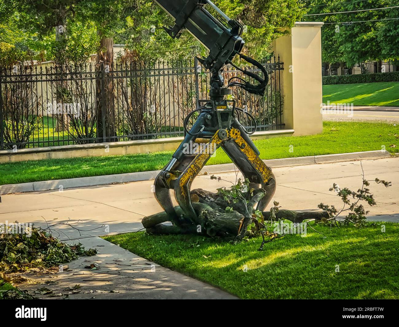 Grapple hook on crane picking up logs -storm debris in upscale neighborhood Stock Photo