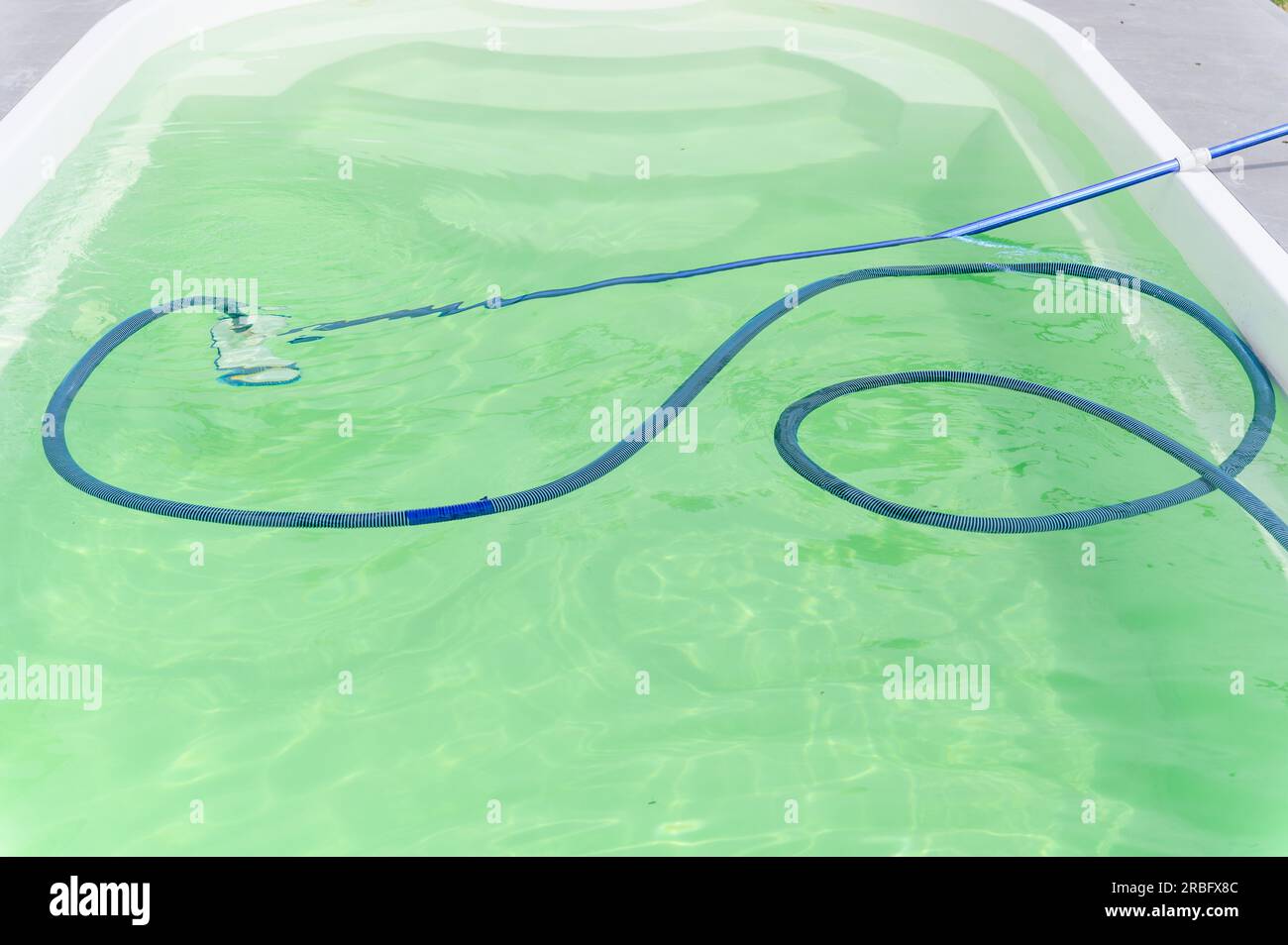 Cleaning bottom of swimming pool by underwater vacuum cleaner. View