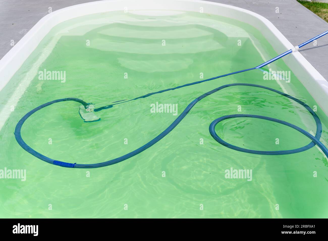 Cleaning bottom of swimming pool by underwater vacuum cleaner. View