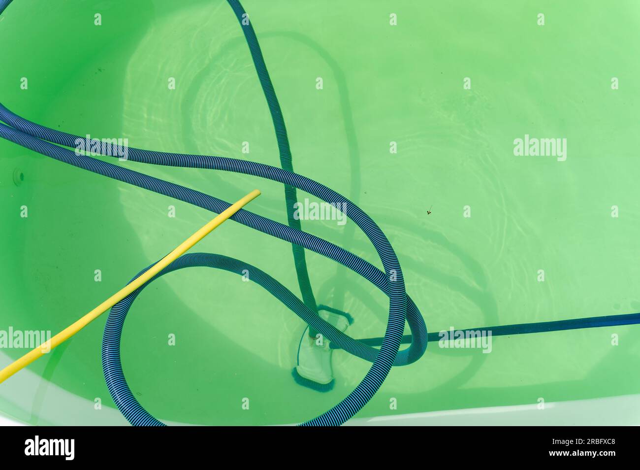 Cleaning bottom of swimming pool by underwater vacuum cleaner. View