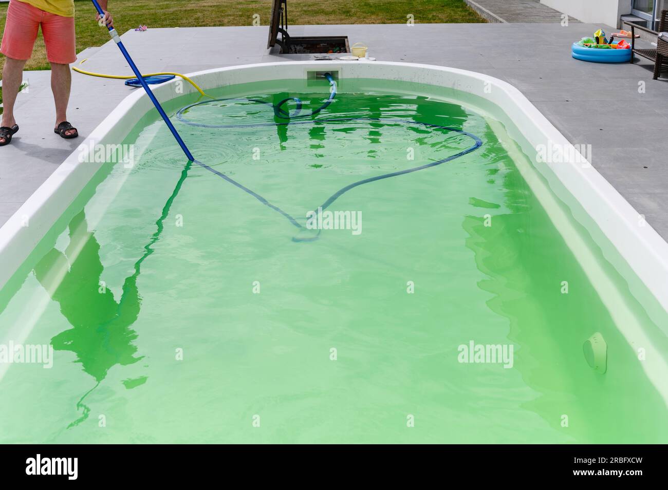 Man cleaning bottom of swimming pool by underwater vacuum cleaner Stock