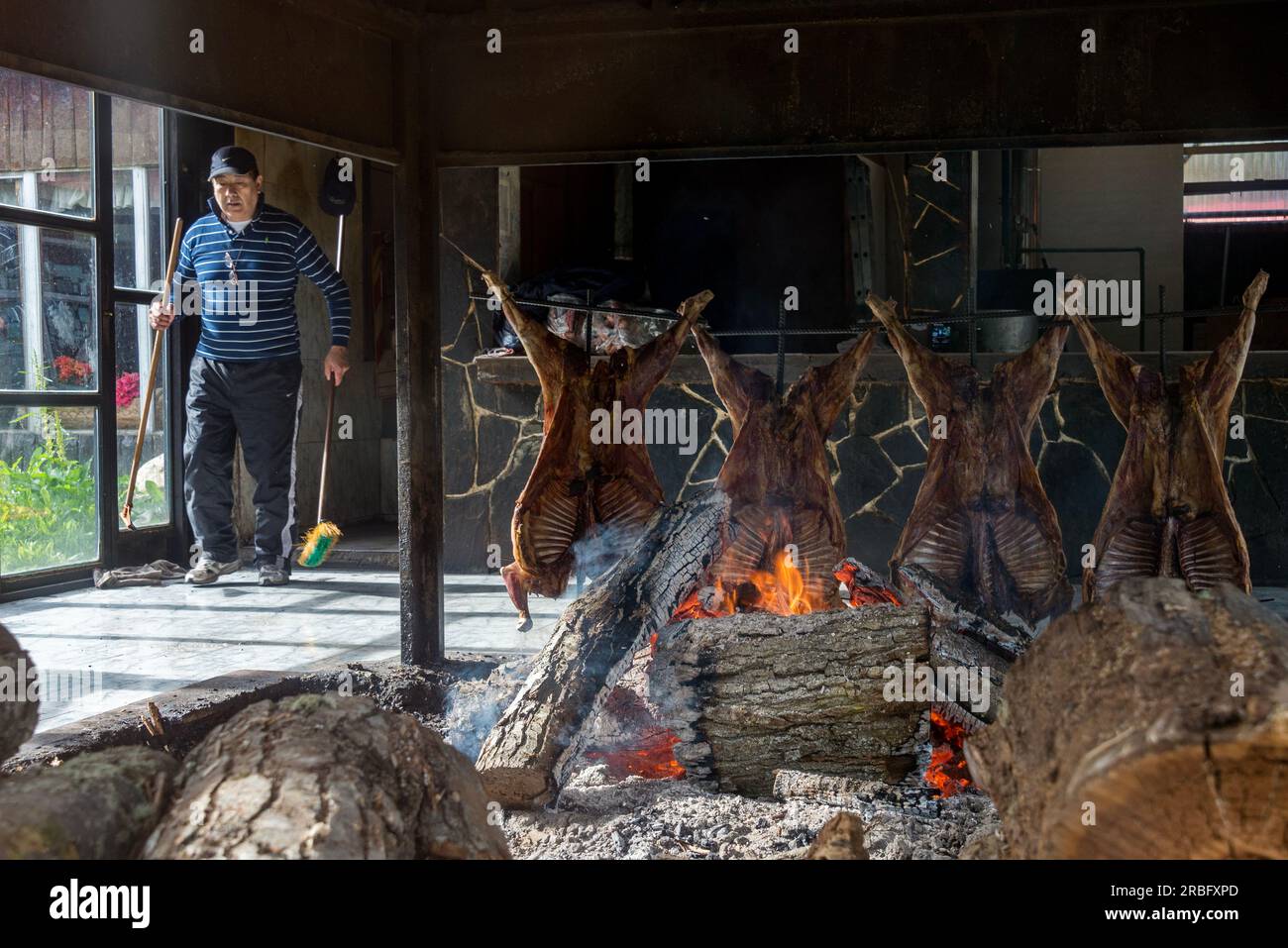 Man cooking the famous Fuegian lamb with a barbecue inside a restaurant, in Ushuaia, Argentina Stock Photo