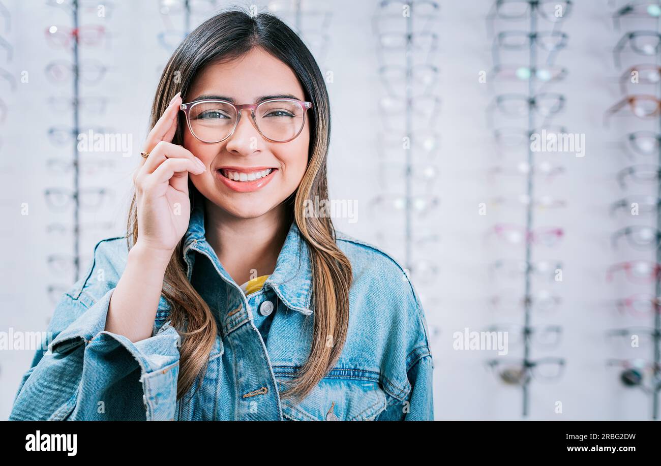 Portrait of beautiful girl modeling glasses in an optical store. Happy