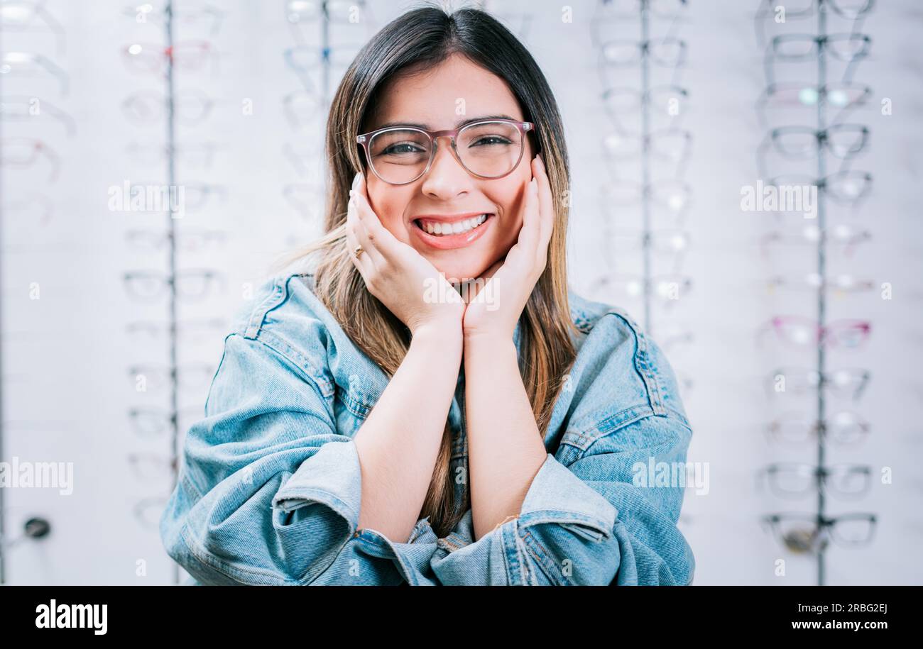 Happy girl modeling glasses in an optical lens store. Portrait of