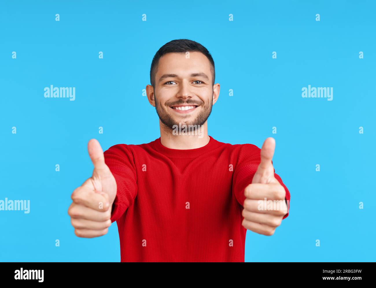 Happy handsome man showing thumbs up sign on blue background. Good idea