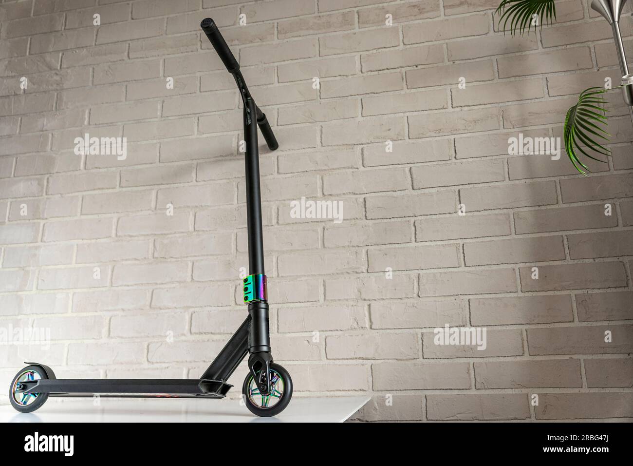 Side view of a stunt scooter with rainbowcolored wheels against a