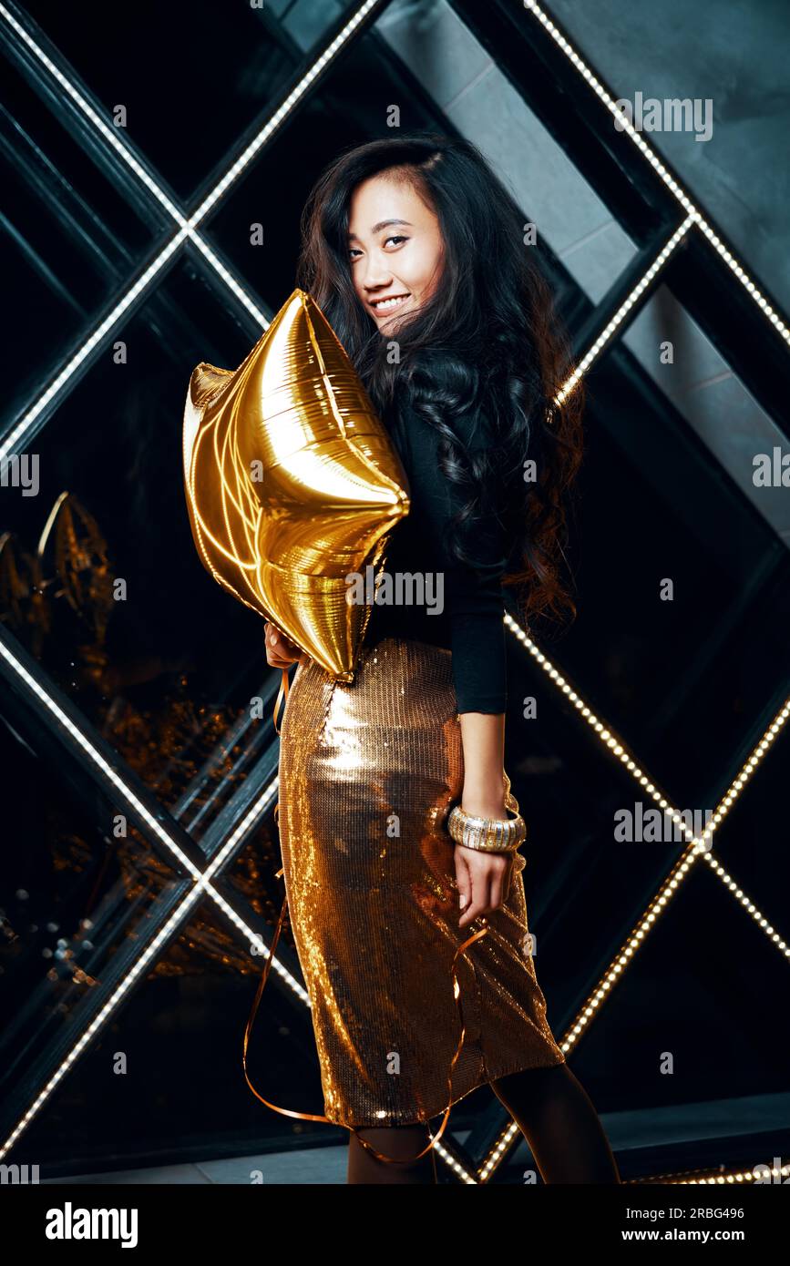 Portrait of pretty happy asian woman having fun and holding golden balloon. Party time, celebration concept Stock Photo