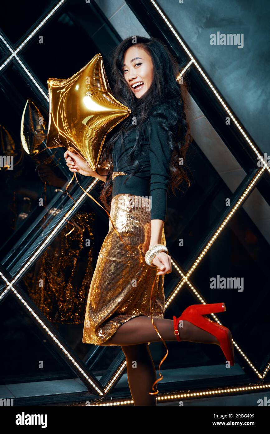Portrait of pretty happy asian woman having fun and holding golden balloon. Party time, celebration concept Stock Photo