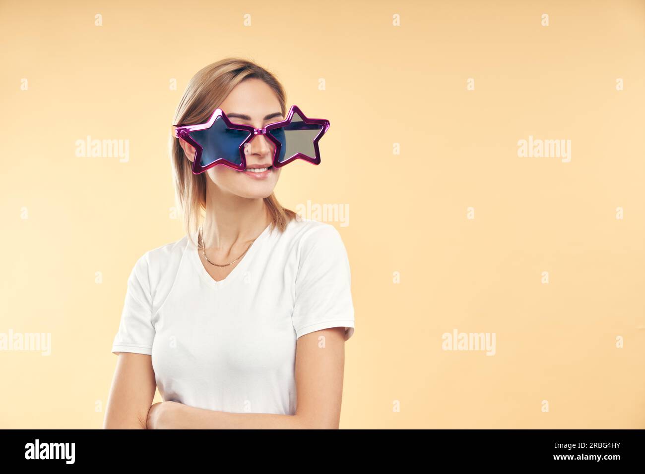 Young pretty woman in party star shape glasses on beige background with copy space Stock Photo