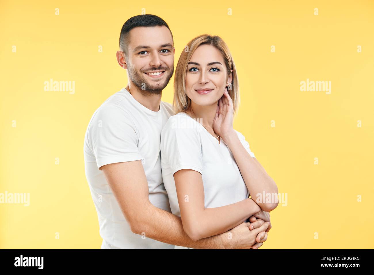 Young happy couple hugging over yellow background. Relationship concept Stock Photo