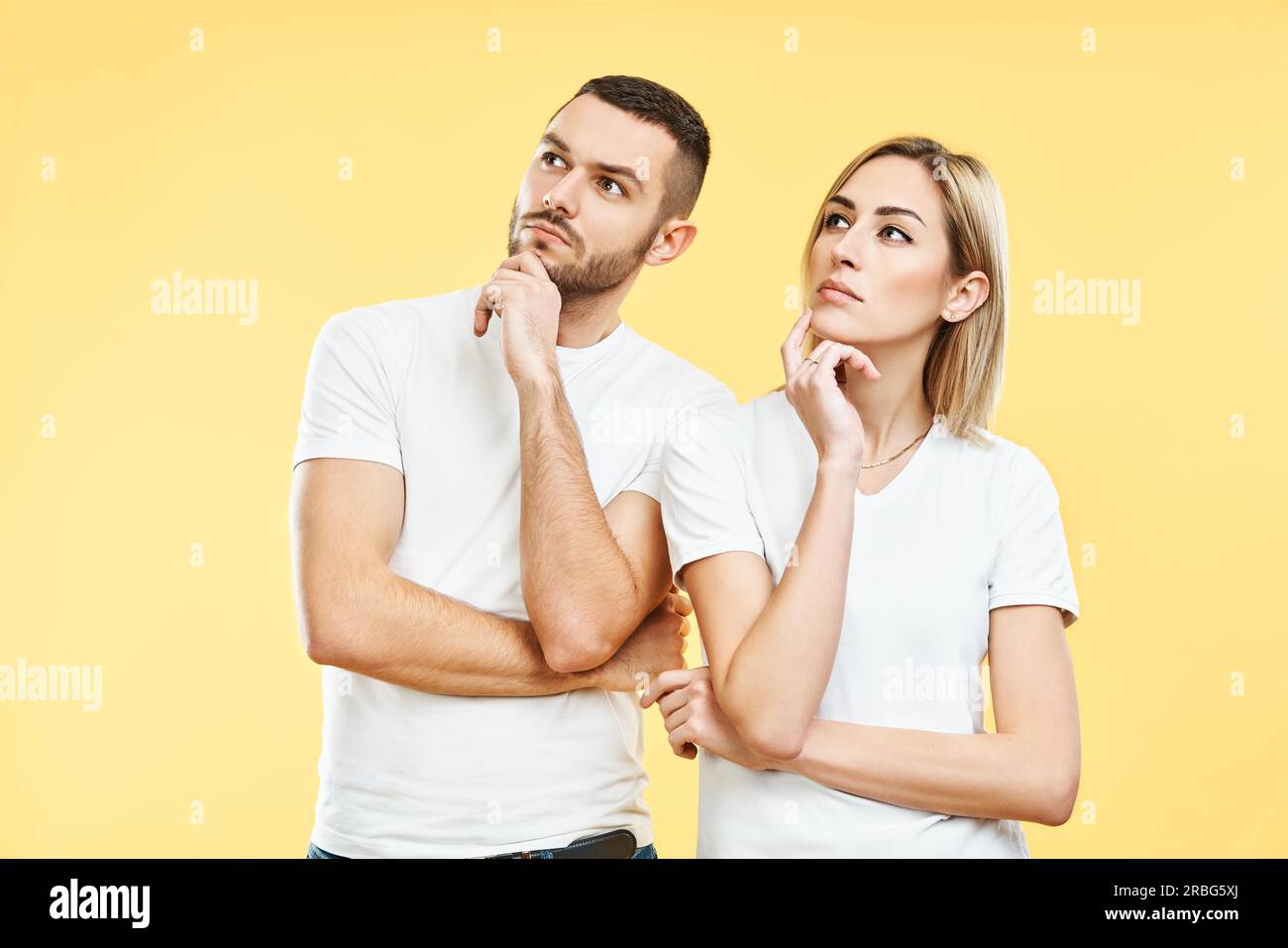 Young thoughtful man and woman looking sideways isolated on yellow background. doubt concept Stock Photo