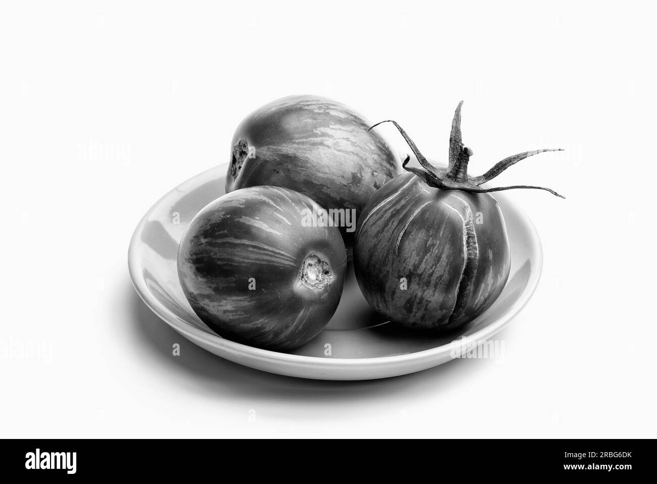 Three juicy zebra tomatoes in a little porcelain plate, isolated on white background Stock Photo