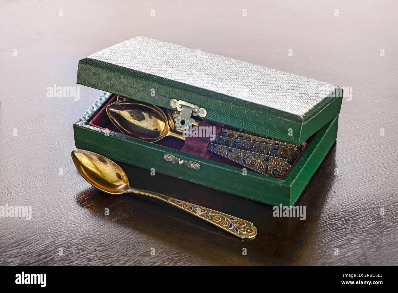 An antique golden spoons case on a wooden table Stock Photo