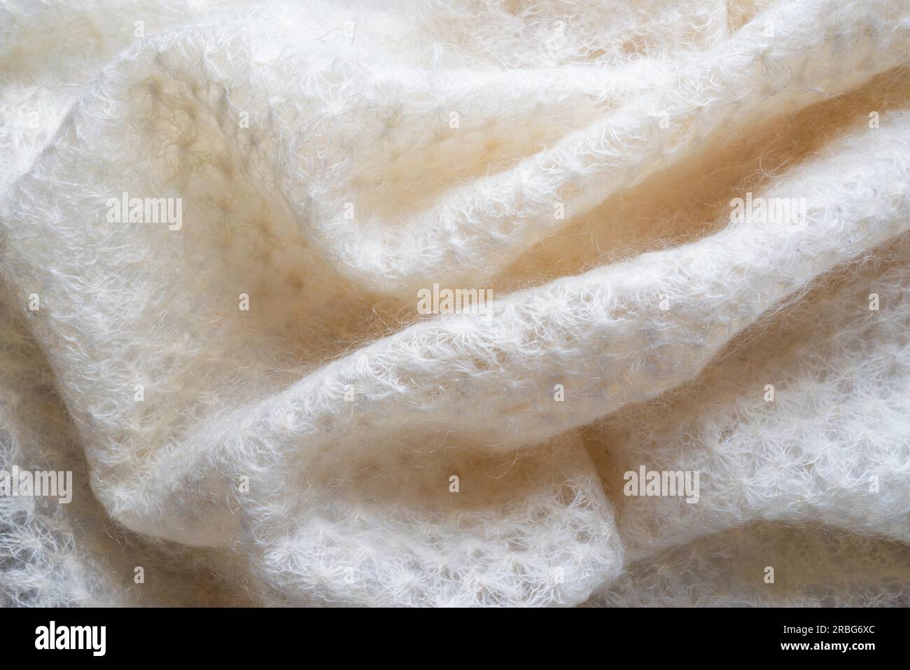 Soft folds of a white goat fluff scarf to be used as background Stock Photo