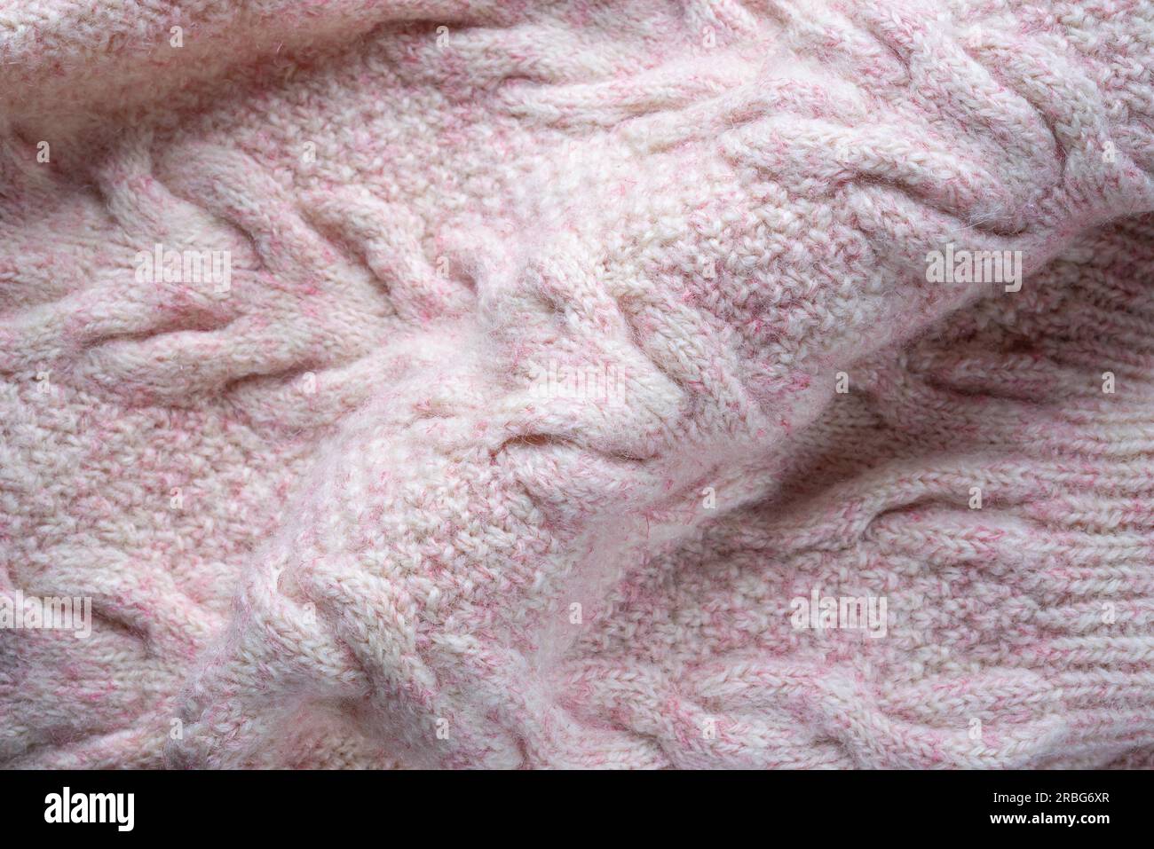 Soft folds of a warm pink knitted woolen pullover to be used as background Stock Photo