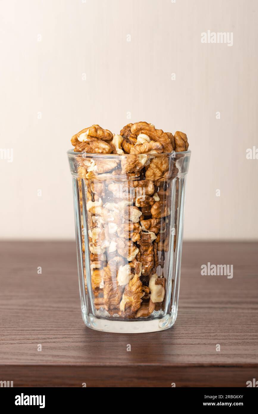 Fresh peeled walnuts in a glass on a wooden table, with negative space for copy text Stock Photo