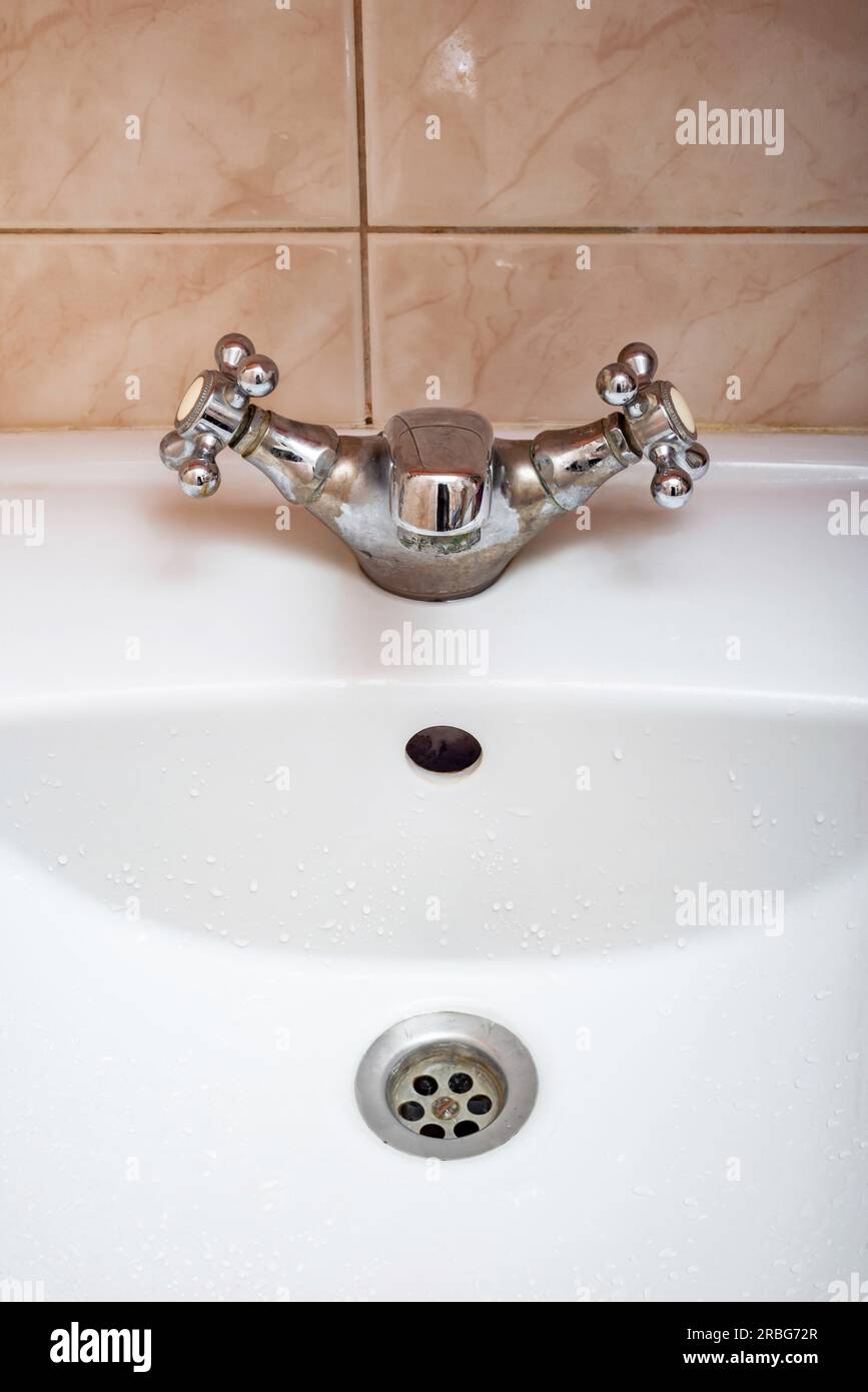 Vertical image of closed tap over a white bathroom sink Stock Photo