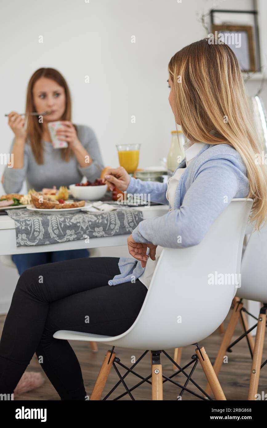 Mother and teenage daughter enjoying breakfast as they spend quality time together having a heart to heart conversation Stock Photo