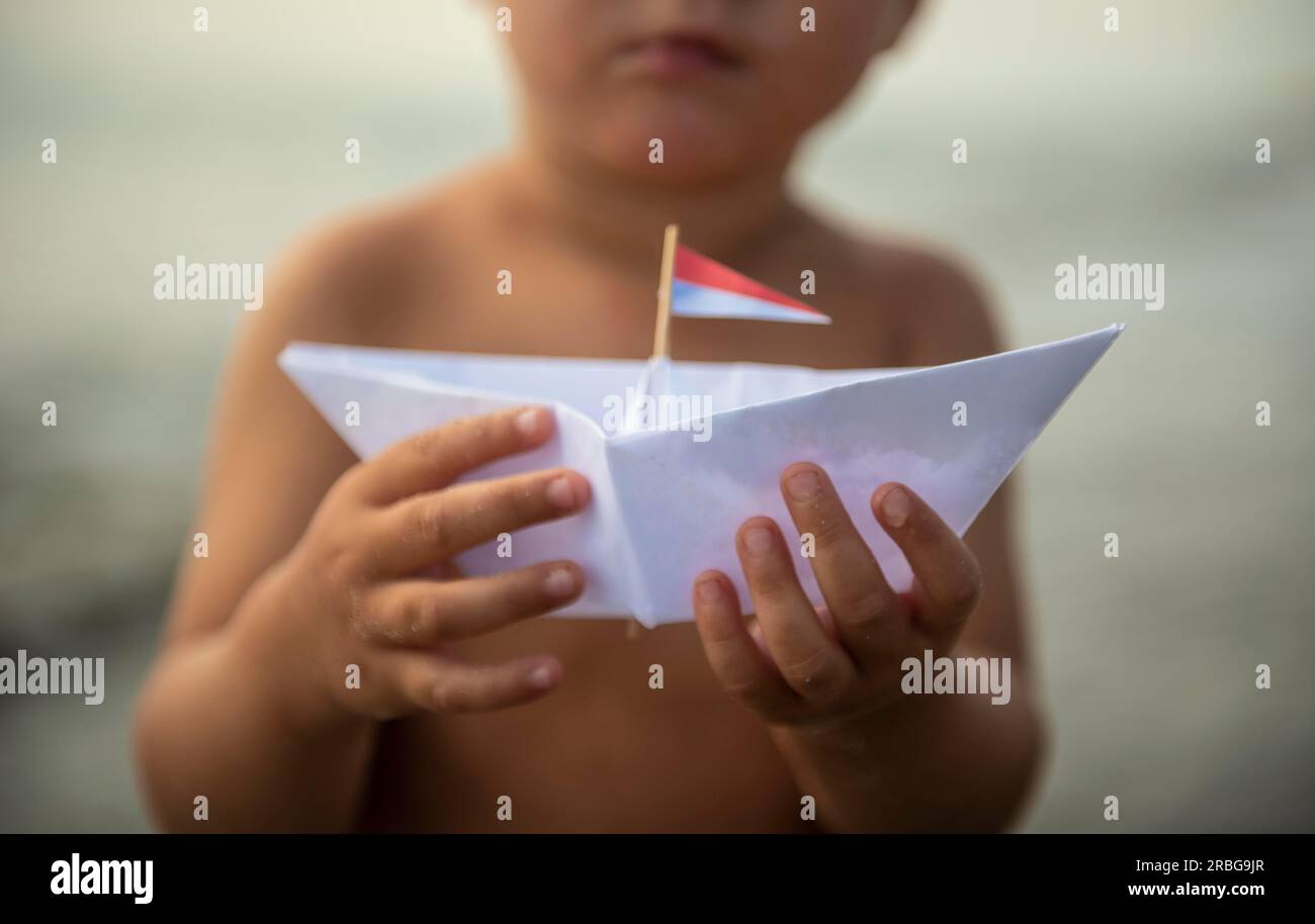 Small child holding paper boat Stock Photo