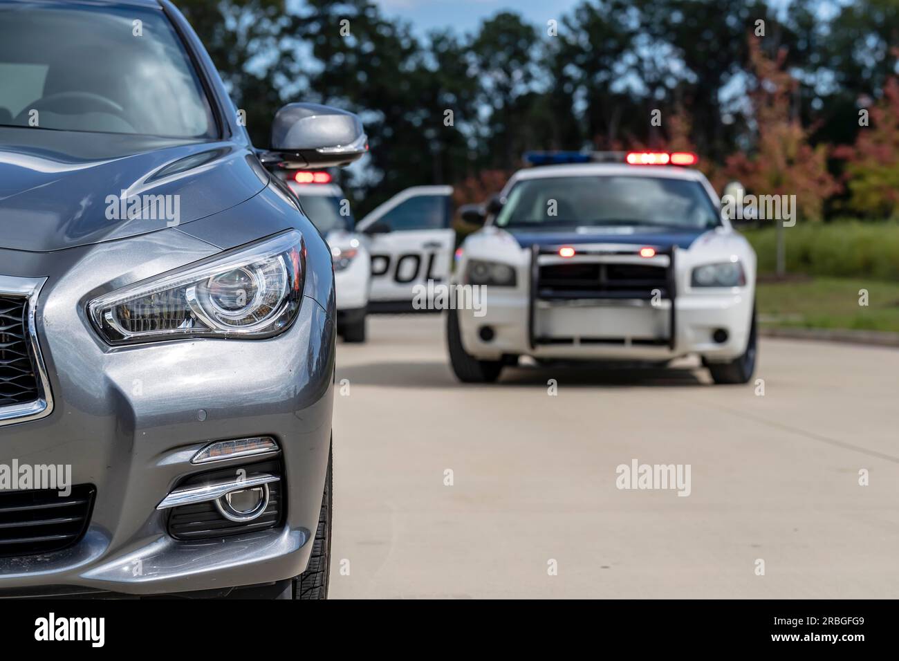 Two Police Vehicles Stop A Sedan On A Routine Traffic Stop Stock Photo