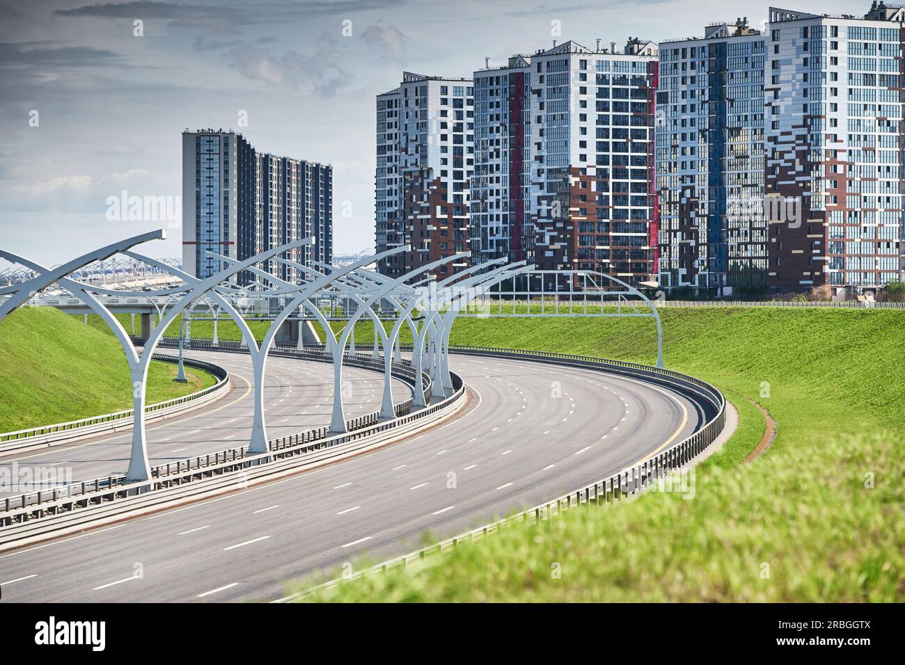Empty expressway of the western high-speed diameter in st. petersburg in clear sunny weather, green lawns along the road, new residential buildings Stock Photo