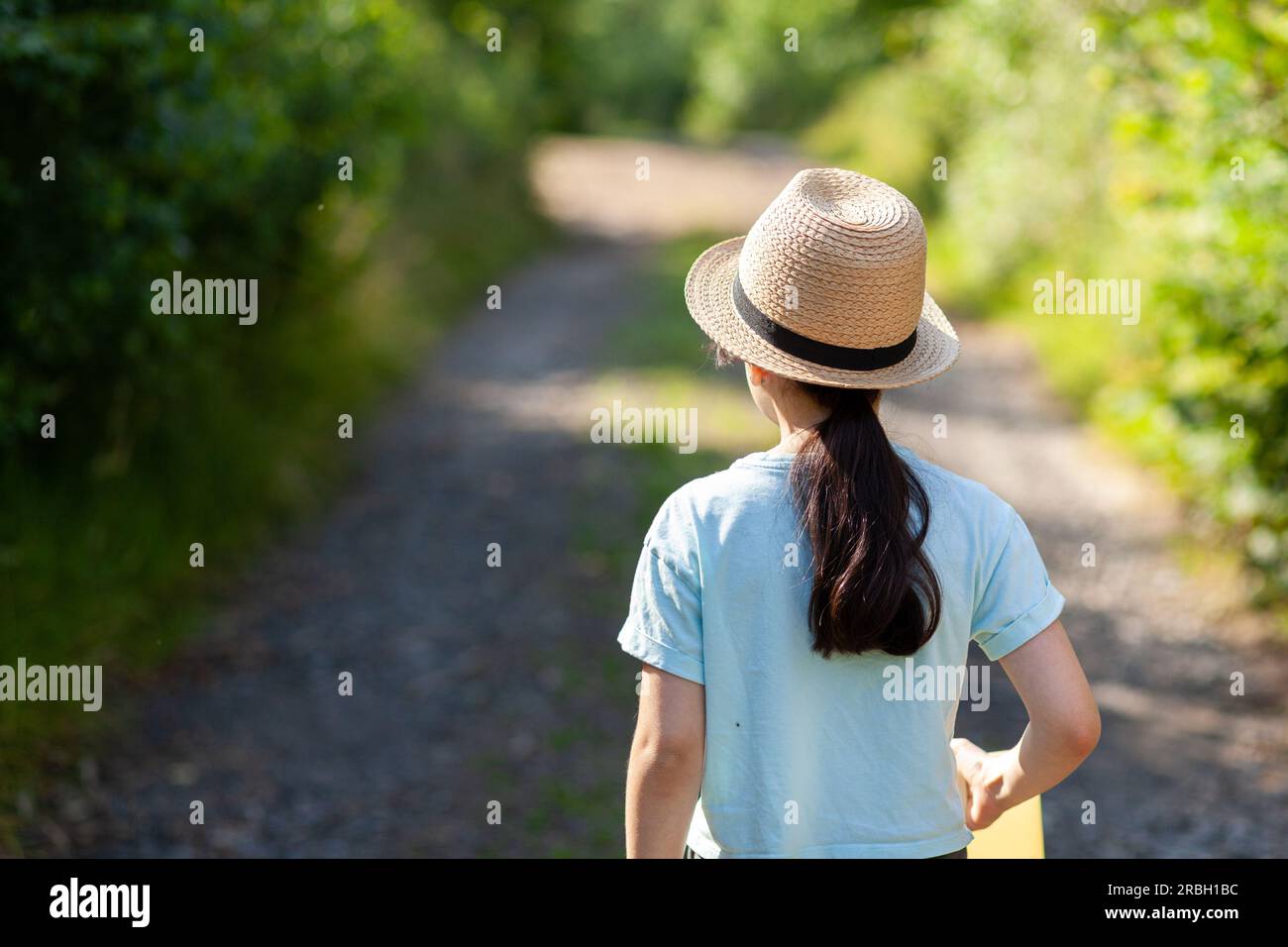 Young woman wearing a straw hat in the park. Back view Stock Photo - Alamy