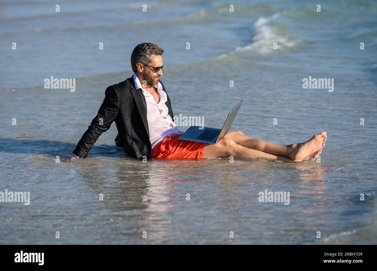 businessman relax at beach. businessman in suit with laptop in summer. Businessman dreams on summer business in sea. Summer business. Businessman rela Stock Photo