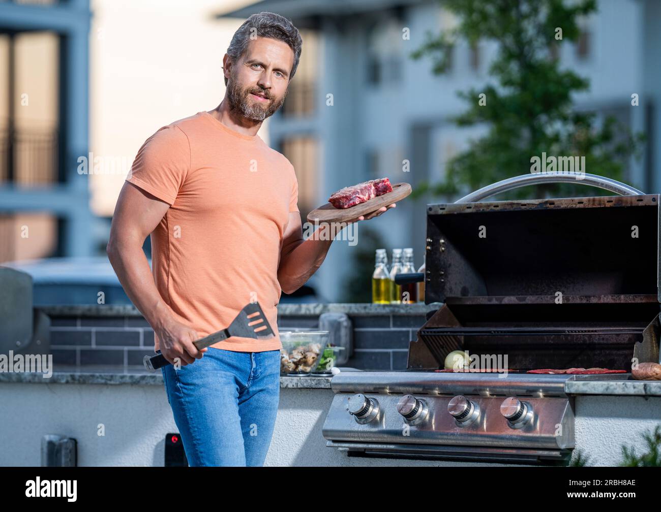 barbecue man grilling meat sirloin steak at outdoor backyard grill bbq. Stock Photo